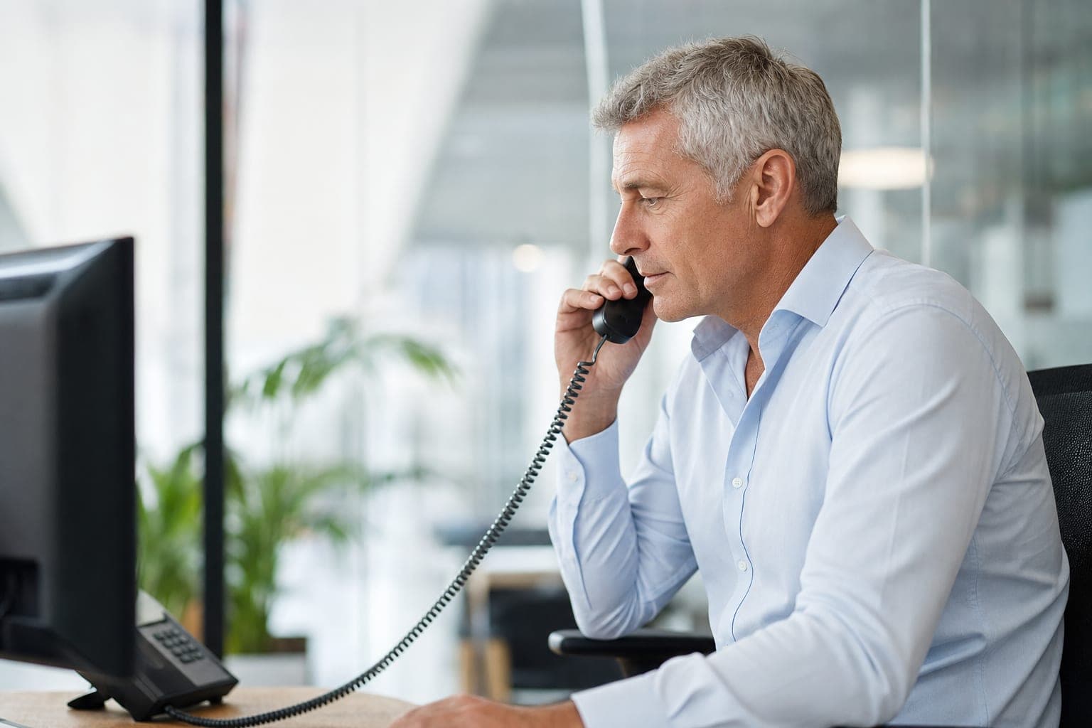 Mitarbeiterin im Telefonat am Schreibtisch, bereit für Ihr Erstgespräch